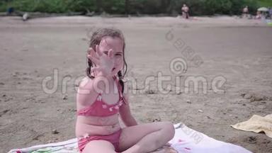 小女孩坐在沙滩上，炎炎夏日.. 挥手微笑